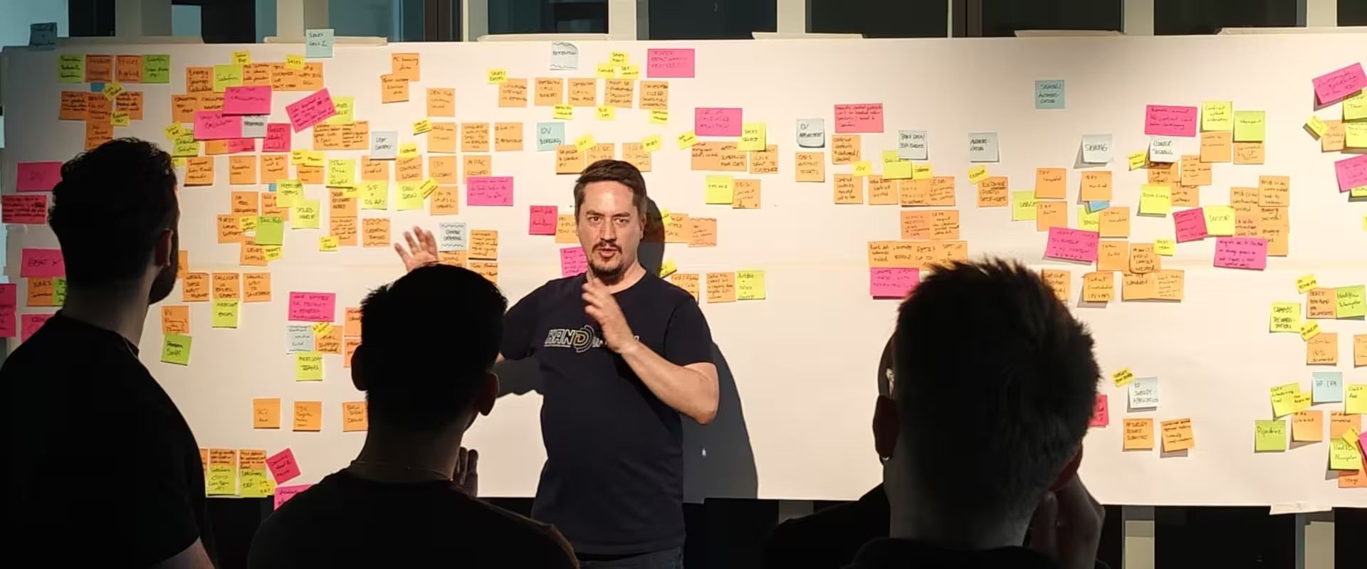 Marco Heimeshoff in action during a workshop and a wall covered of sticky notes